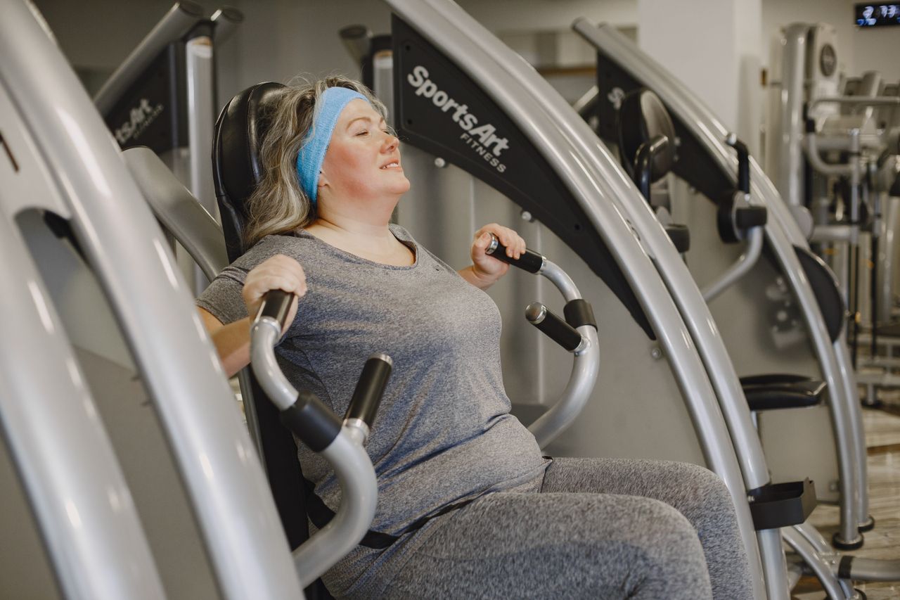 about-us-02 Plus size woman working out on gym equipment indoors, promoting health and wellness.